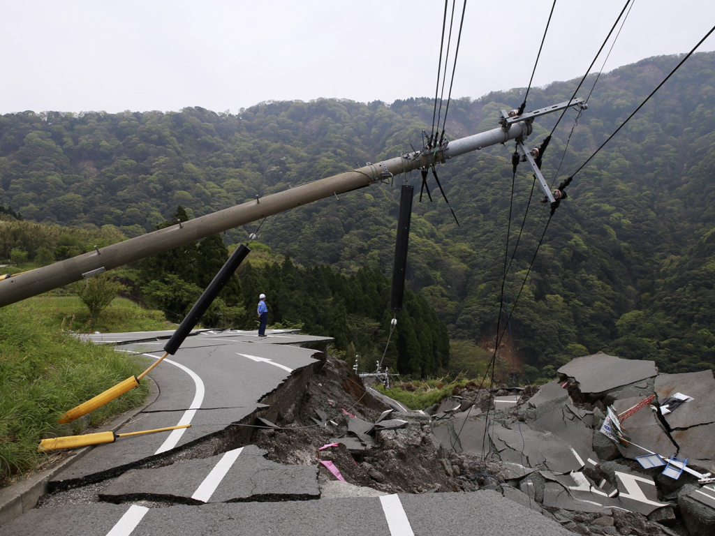 地震で電柱が倒れて地面がひび割れている